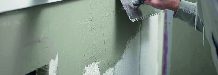 Person spachtelt Wand mit Kelle